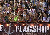  Student section cheering at football game and holding a Flagship banner.